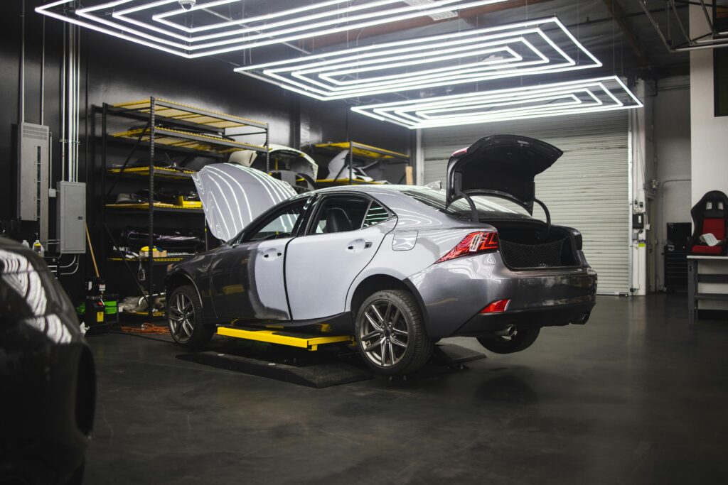 Gray car undergoing repairs in a sleek, modern auto repair shop environment.