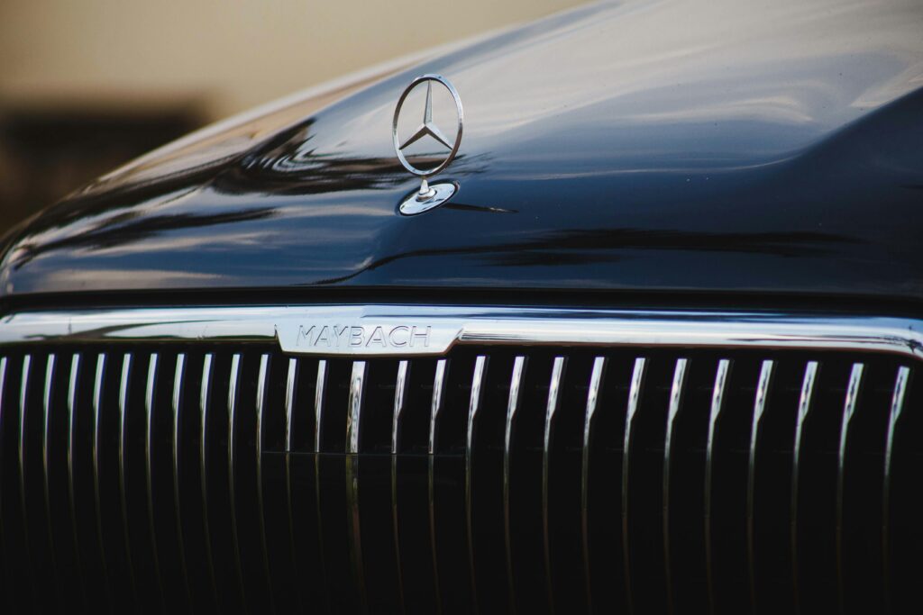 Detailed view of a luxury car's grille with brand emblem, reflecting elegance and sophistication.