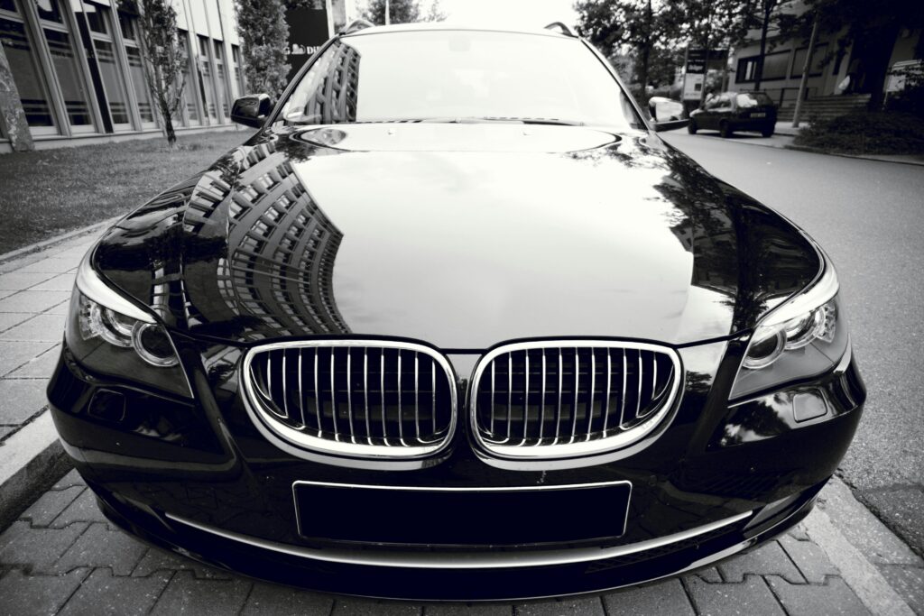 pexels photo 358208 358208 Front view of a shiny black luxury sedan reflecting city buildings, showcasing elegance and style.